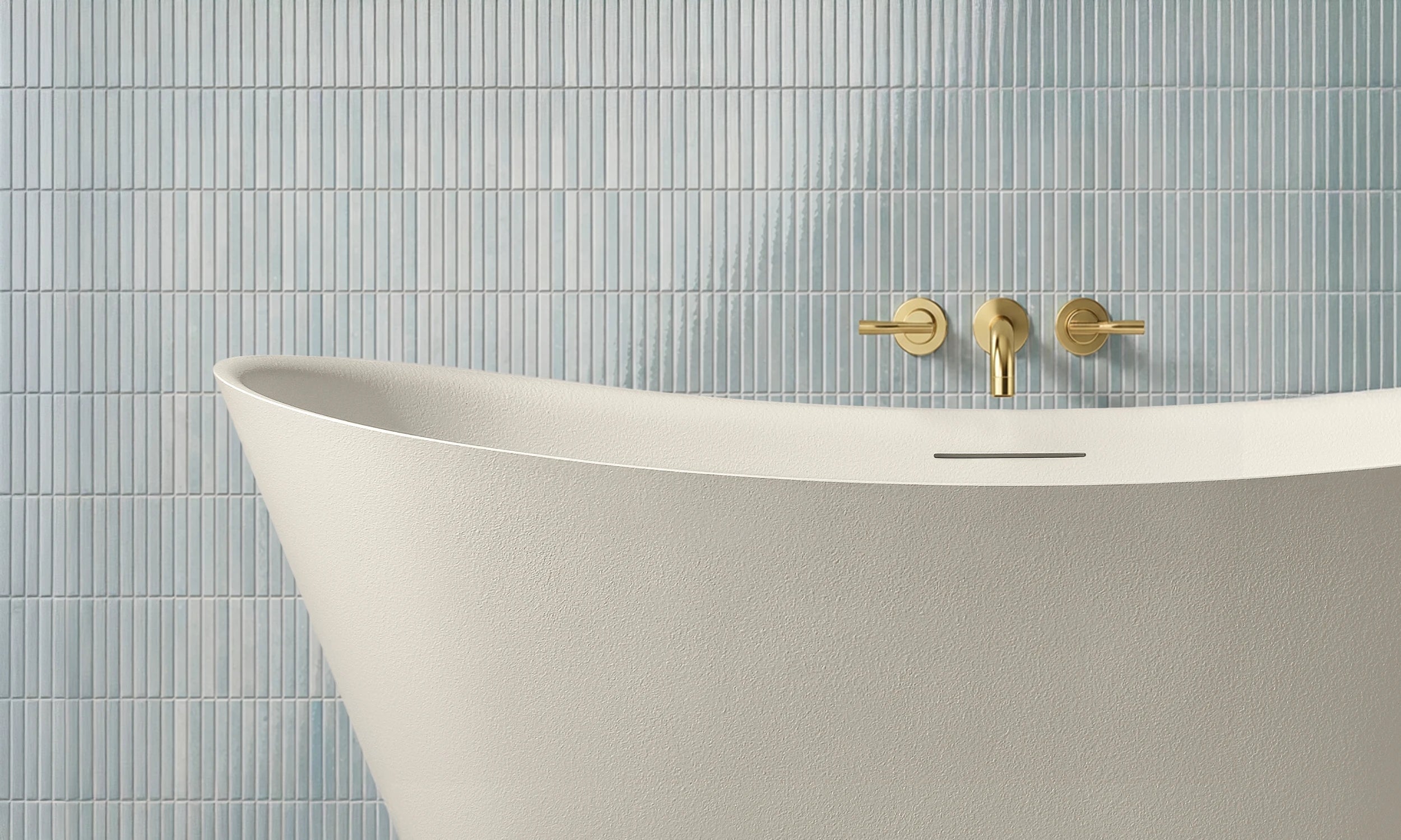 White ARCHA freestanding bathtub with gold faucet and handles against a light blue tiled wall.