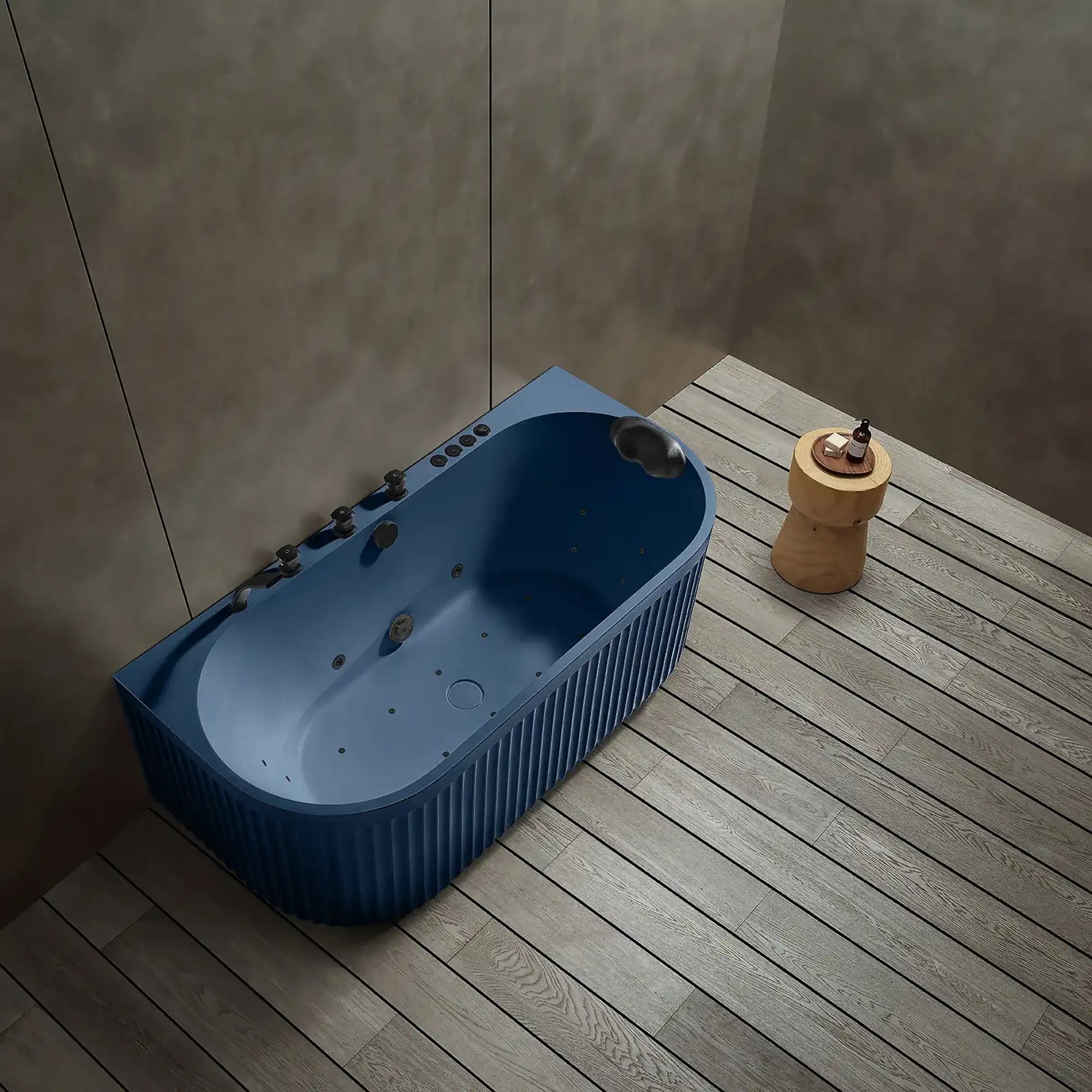 A top view of the Doria spa bathtub in Prussian blue with black tapware, in a modern bathroom with wooden floor and gray walls.