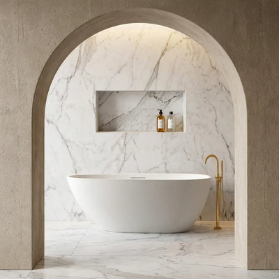Modern bathroom with the ARIA 1700mm freestanding bathtub in white, marble walls, and gold fixtures. 