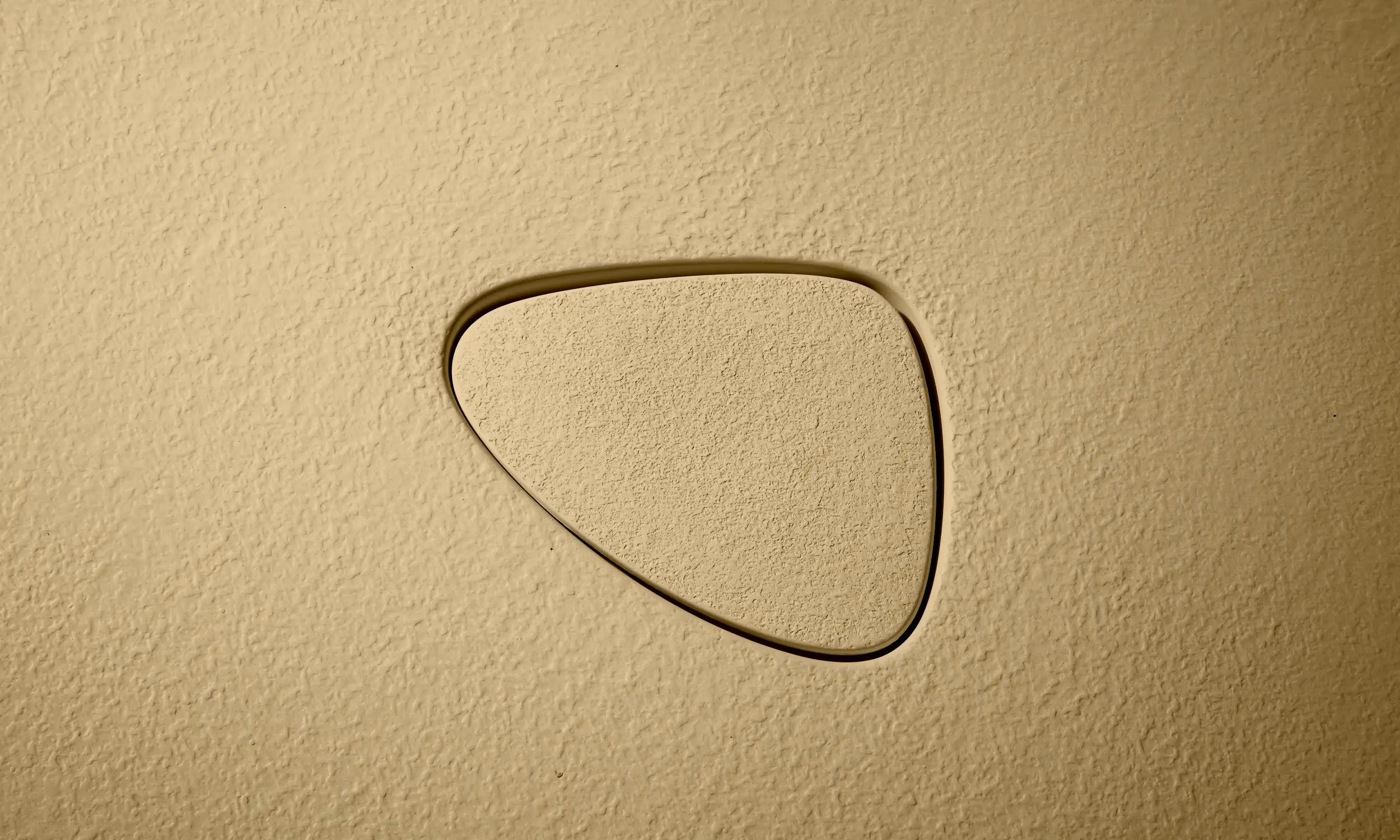 Close up of the pop-up waste of a Bellastone bath in caramel colour, showing the disctinct texture of the material